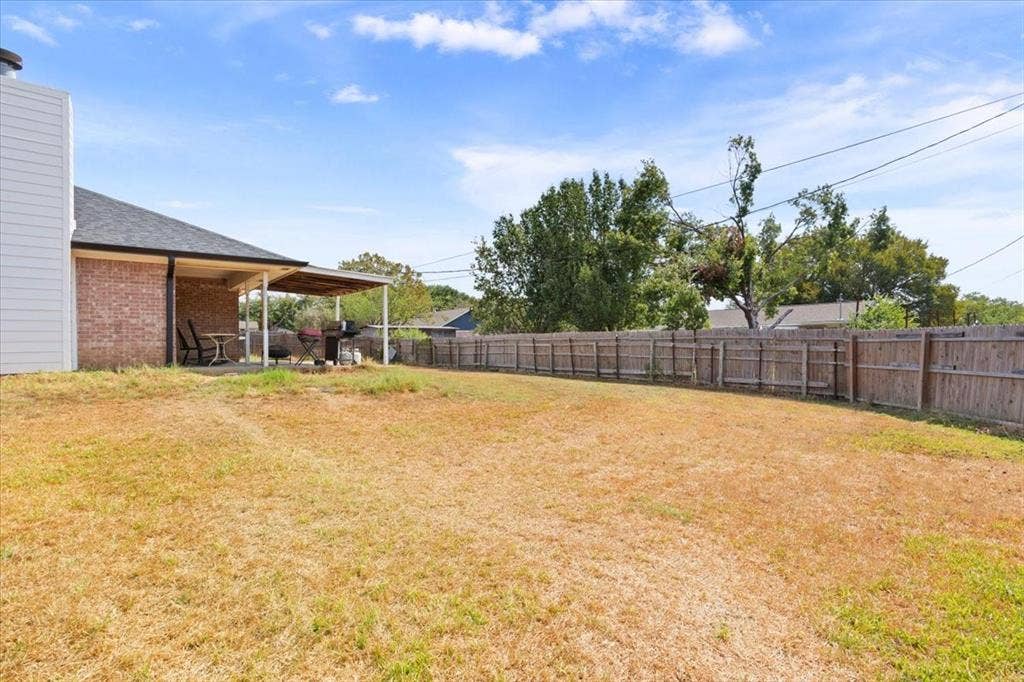 Expansive backyard featuring a wood fence perimeter and a covered concrete patio