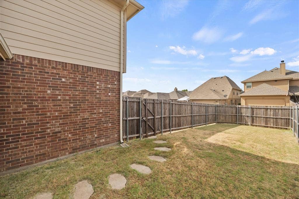 1225 Honeywood Lane, Royse City, TX 75189 Expansive fenced backyard featuring a stone paver pathway and a brick and siding exterior