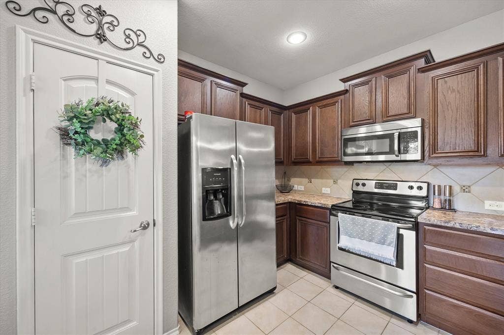 1225 Honeywood Lane, Royse City, TX 75189 Kitchen featuring wood cabinetry, stainless steel appliances, tile flooring, and a tile backsplash