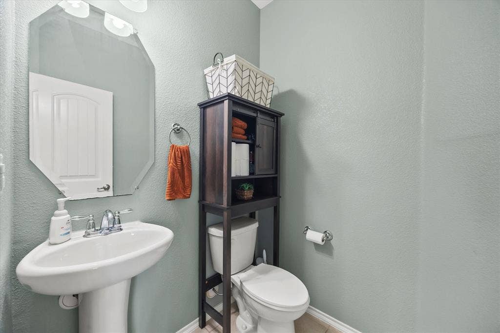 1225 Honeywood Lane, Royse City, TX 75189 Pedestal sink with chrome faucet, octagonal wall mirror, and built-in over-the-toilet storage cabinet