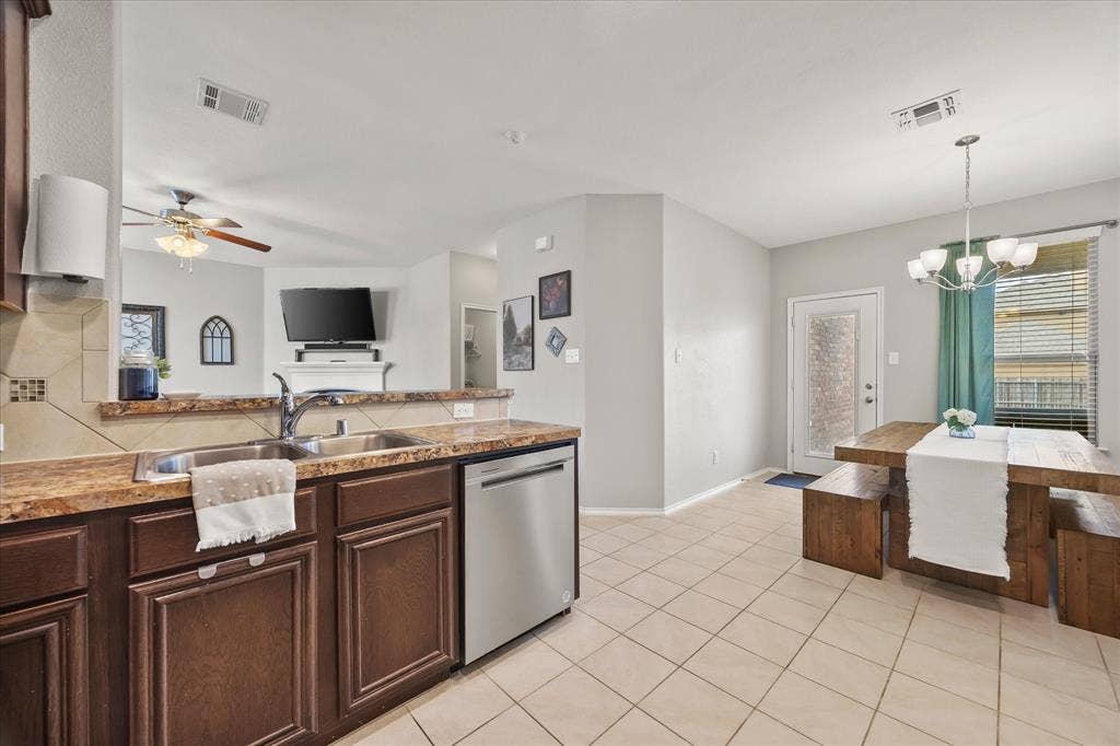 1225 Honeywood Lane, Royse City, TX 75189 Open-concept kitchen and dining area featuring a tile backsplash, stainless steel dishwasher, double basin sink, and a multi-light chandelier