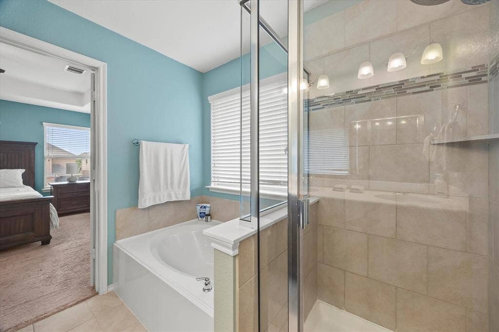 1225 Honeywood Lane, Royse City, TX 75189 Built-in soaking tub, glass-enclosed shower with tiled walls, decorative tile shower accent, and a row of four vanity lights