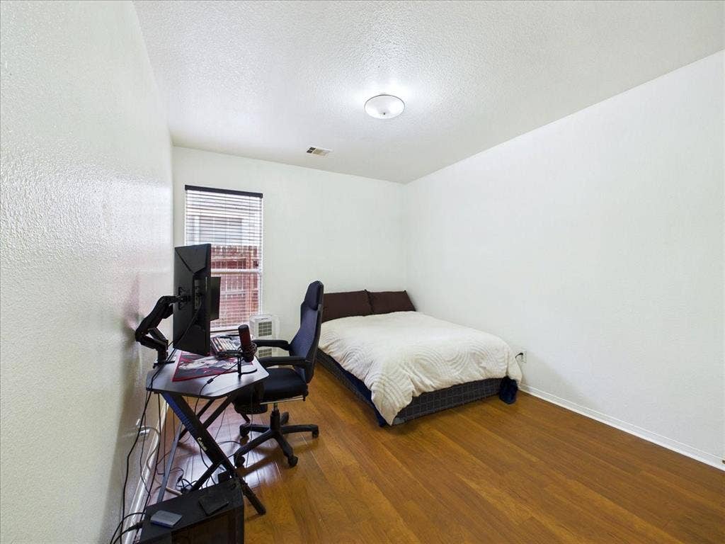 Wood-finish flooring throughout, white painted walls, and a window with blinds