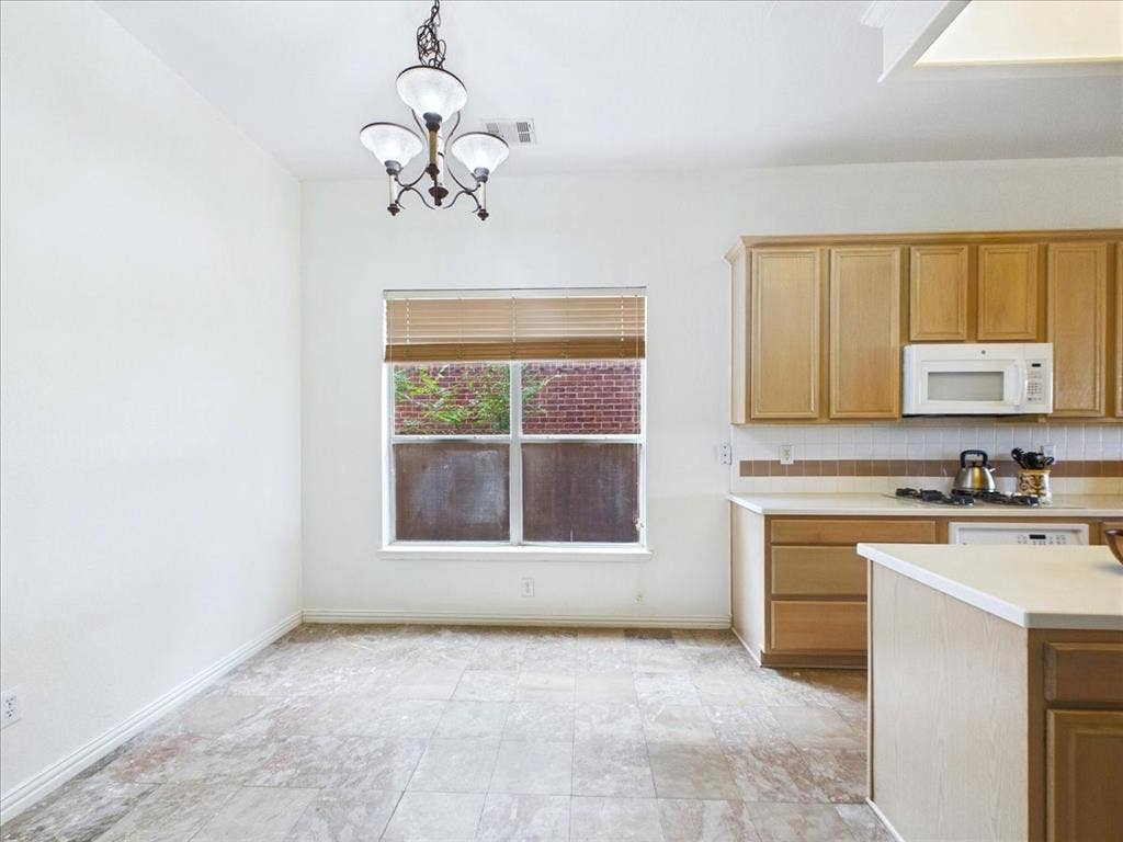 Tiled flooring, built-in cabinetry, window with blinds, overhead lighting fixture, and a built-in microwave