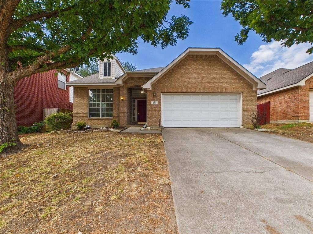 Brick exterior, attached garage, gabled roofline, dormer window, concrete driveway