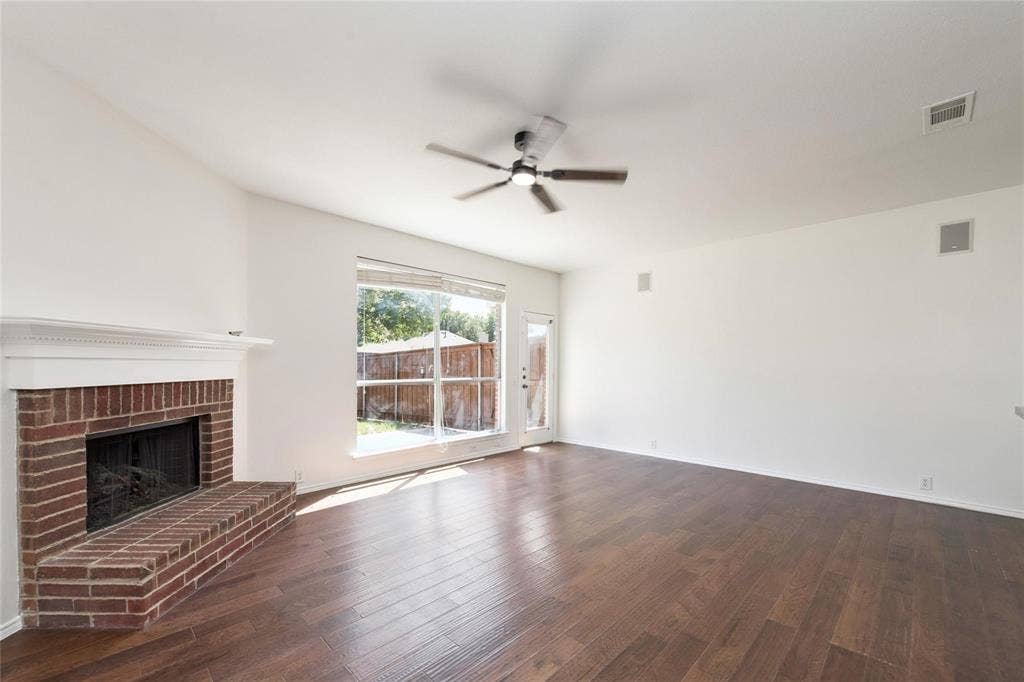 11443 Waterford Lane, Frisco, TX 75035 Vaulted ceiling with a ceiling fan, brick fireplace with mantel, wood-finish flooring, and a large window with a backyard view