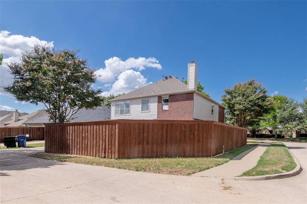 11443 Waterford Lane, Frisco, TX 75035 Corner lot property featuring a wood privacy fence, brick and siding exterior, and a visible chimney