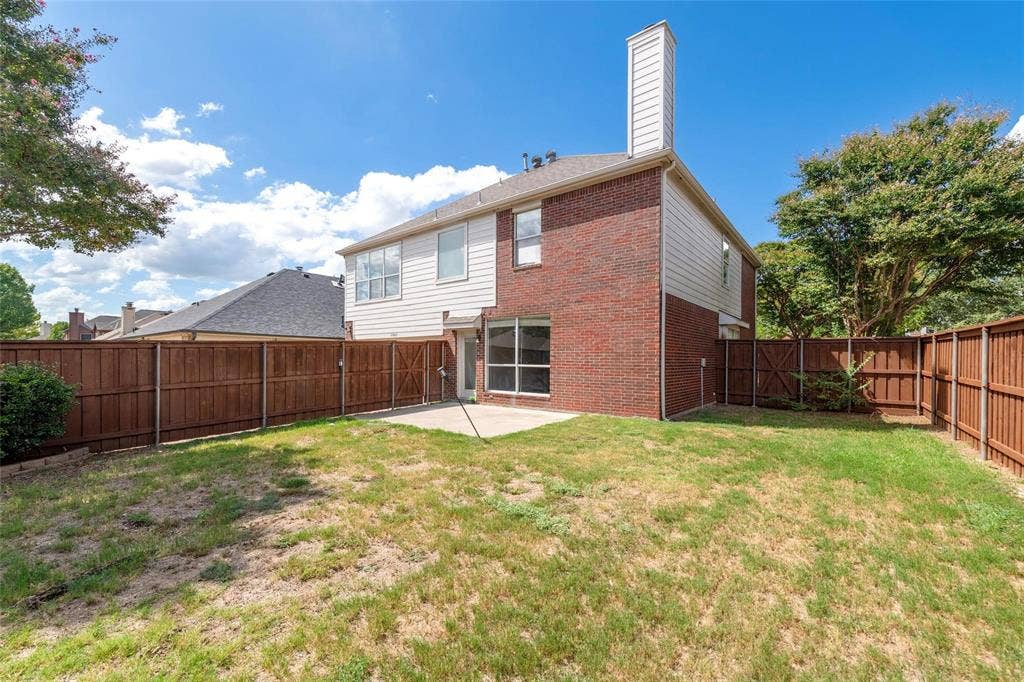 11443 Waterford Lane, Frisco, TX 75035 Backyard featuring a concrete patio, wood privacy fencing, and a two-story brick and siding exterior