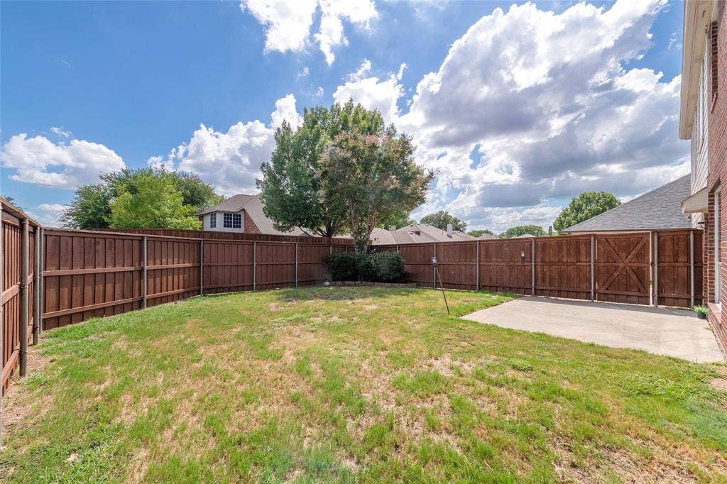 11443 Waterford Lane, Frisco, TX 75035 Expansive fenced backyard featuring a concrete patio, mature trees, and privacy fencing with gate access