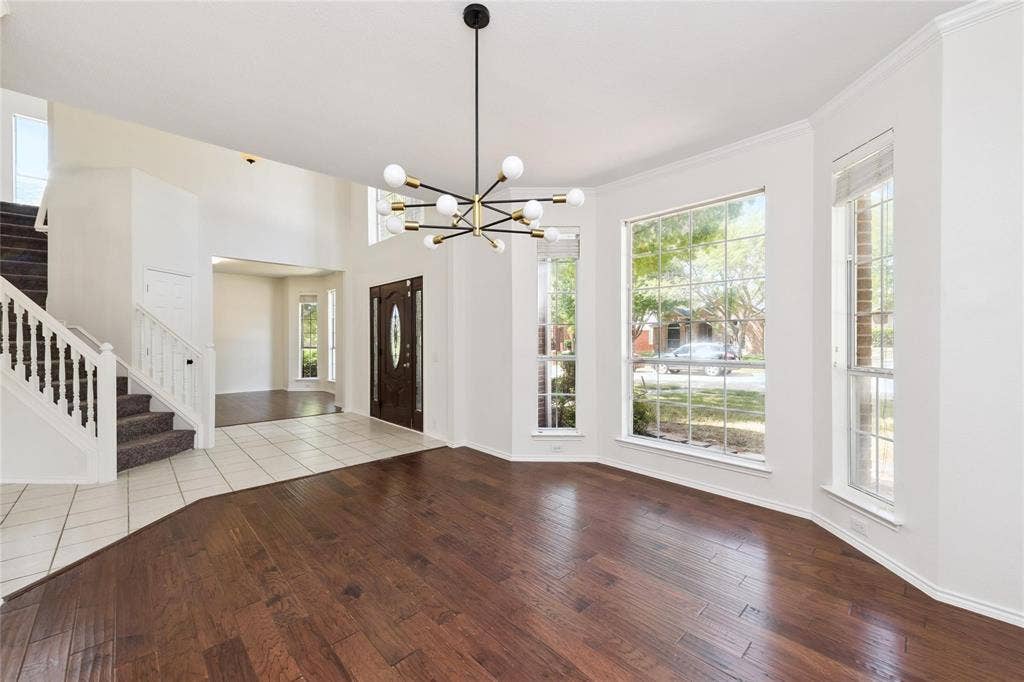 11443 Waterford Lane, Frisco, TX 75035 Hardwood flooring, bay windows, modern chandelier, two-story ceiling, and a grand staircase with white balusters