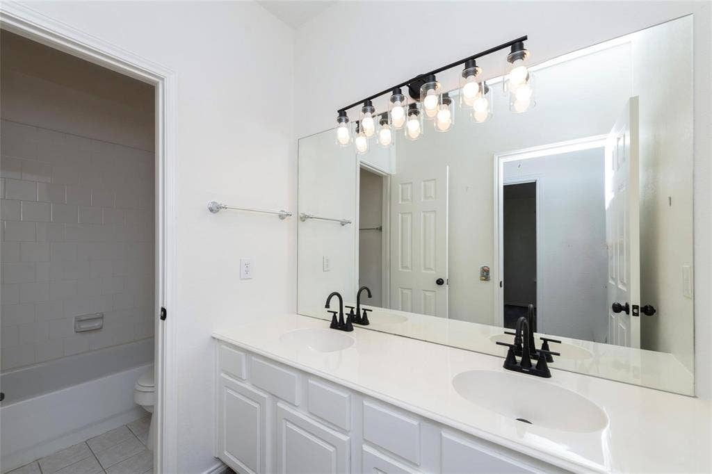 11443 Waterford Lane, Frisco, TX 75035 Dual vanity with white cabinetry, integrated sinks, white countertop, and matte black fixtures
