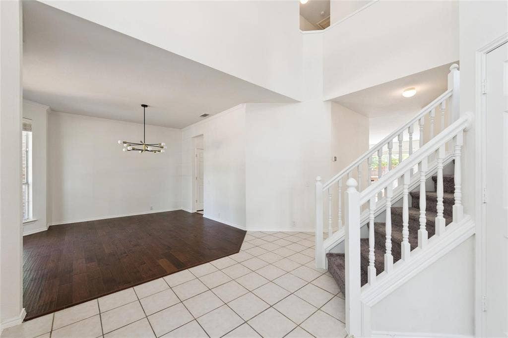 11443 Waterford Lane, Frisco, TX 75035 High ceilings featuring an open foyer, wood-finish flooring, a modern chandelier, and a carpeted staircase with white balusters