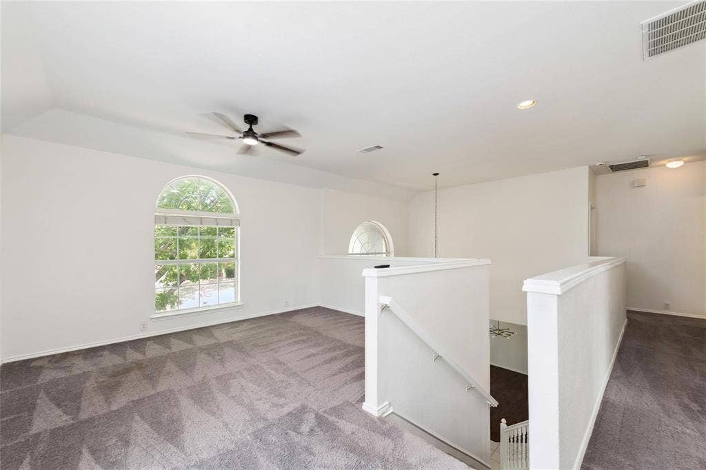 11443 Waterford Lane, Frisco, TX 75035 Carpeted loft area featuring an arched window, ceiling fan, recessed lighting, and a white balustrade overlooking a lower level