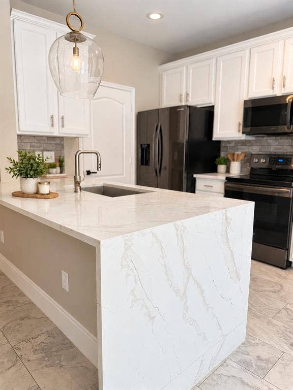 6854 Cortona Lane, Frisco, TX 75034 Kitchen featuring a waterfall-edge island, undermount sink with a gooseneck faucet, white shaker-style cabinetry, and dark-finish appliances