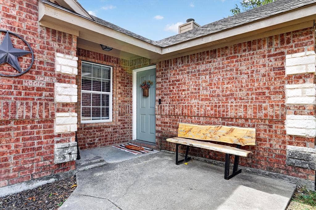 5413 Cornell Avenue, River Oaks, TX 76114 Brick exterior with stone accents, a covered entry, and a window with blinds
