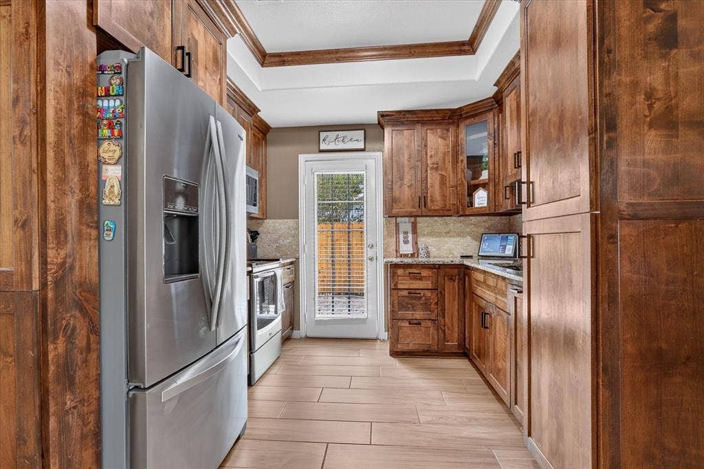 5413 Cornell Avenue, River Oaks, TX 76114 Wood-finish flooring, stainless steel appliances, wood cabinetry, stone countertop, and a glass-paneled door