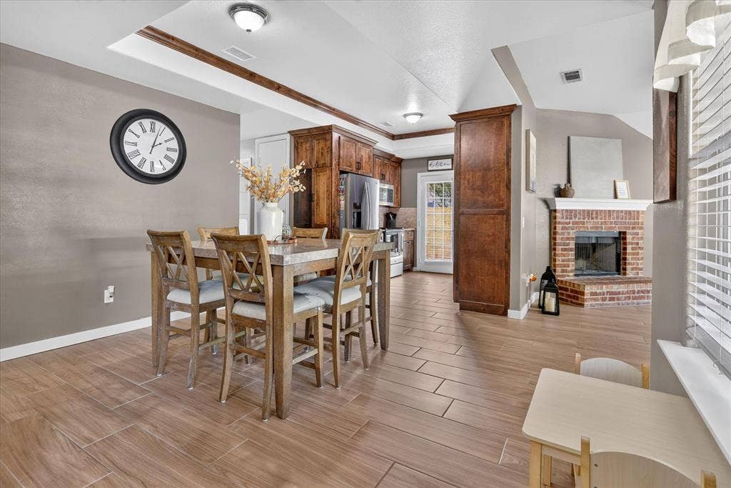 5413 Cornell Avenue, River Oaks, TX 76114 Wood-look tile flooring throughout, featuring a brick fireplace with a white mantel, and a kitchen with wood cabinetry and stainless steel appliances