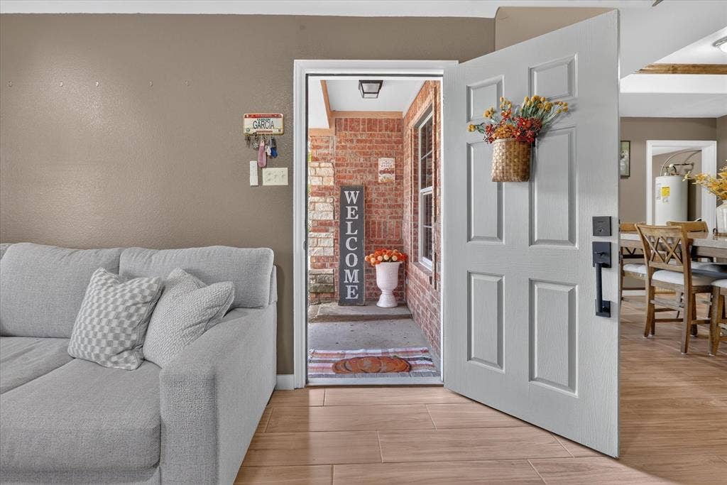 5413 Cornell Avenue, River Oaks, TX 76114 Six-panel entry door with matte black hardware, wood-finish flooring, and brick exterior detailing