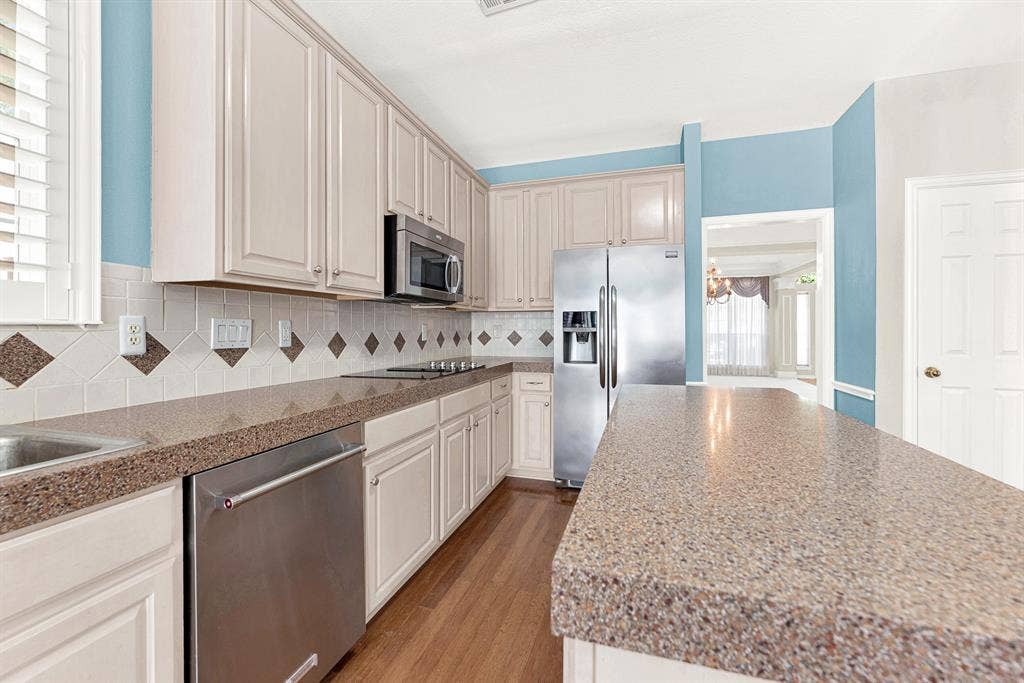 4020 MAYFLOWER Lane, Plano, TX 75024 Expansive speckled countertops extend alongside stainless appliances to offer generous workspace. Perfect for spreading out dough to bake morning pastries with family.