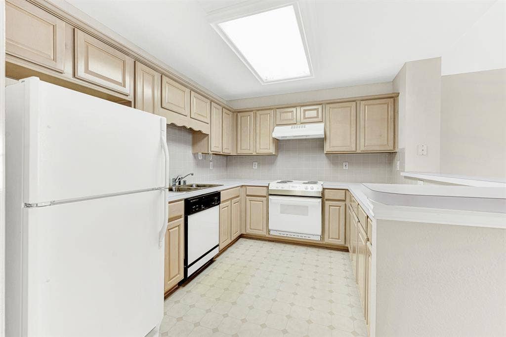 4020 MAYFLOWER Lane, Plano, TX 75024 A fully equipped kitchen features full-sized appliances, light cabinetry, and an overhead skylight. Perfect for preparing independent daily meals or late-night snacks.