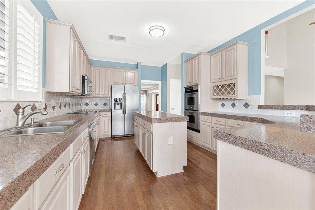 4020 MAYFLOWER Lane, Plano, TX 75024 FABULOUS REMODEL OPPURTUNITY!!! Soft blue accent walls pop against beige cabinetry and a central prep island. It's a wonderful setup for pulling out fresh ingredients to craft gourmet weekend meals.