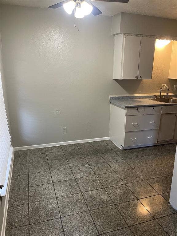 5317 Junius Street, #214, Dallas, TX 75214 Kitchen space featuring square tile flooring, white cabinetry, a stainless steel sink, and a ceiling fan with integrated lighting