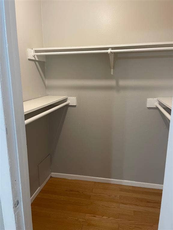 5317 Junius Street, #214, Dallas, TX 75214 Closet featuring wood-finish flooring, white walls, and built-in shelving with hanging rods