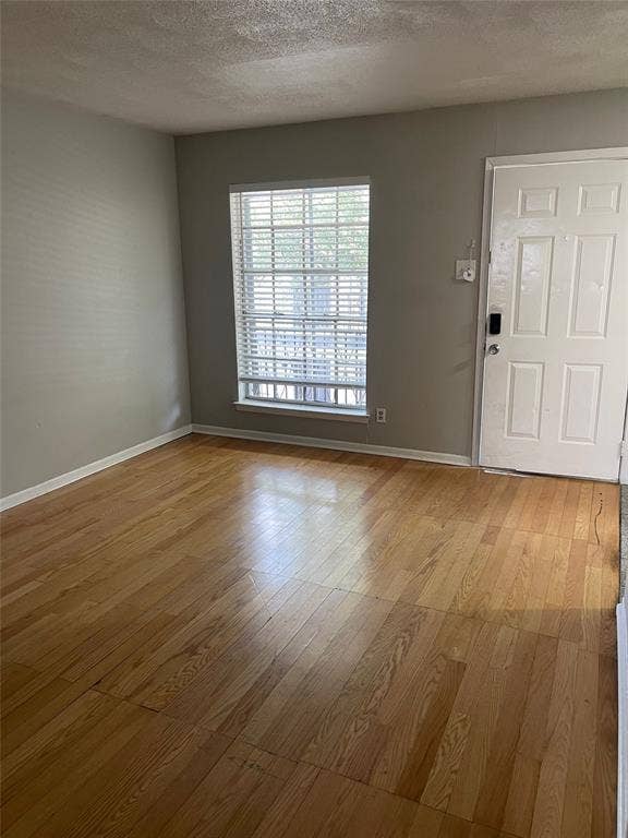 5317 Junius Street, #214, Dallas, TX 75214 Wood-finish flooring, white paneled entry door, and window with blinds