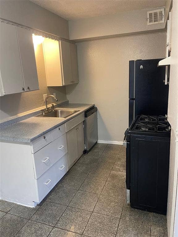 5317 Junius Street, #214, Dallas, TX 75214 Kitchen featuring tile flooring, a stainless steel sink, a dishwasher, a black refrigerator, and a black range with an oven