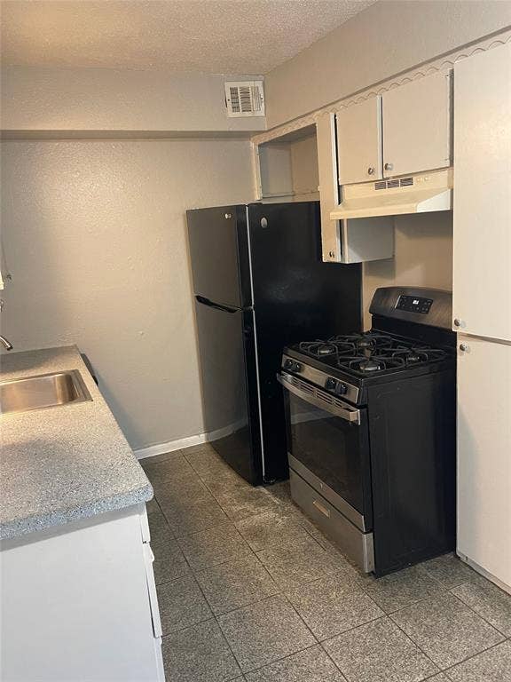 5317 Junius Street, #214, Dallas, TX 75214 Black refrigerator, stainless steel range, white cabinetry, integrated sink, and tile flooring