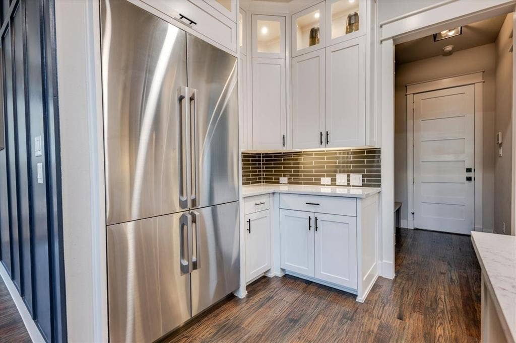 4102 Parkview Boulevard, Celina, TX 75009 Stainless steel refrigerator, white shaker-style cabinetry, subway tile backsplash, under-cabinet lighting, and wood-finish flooring