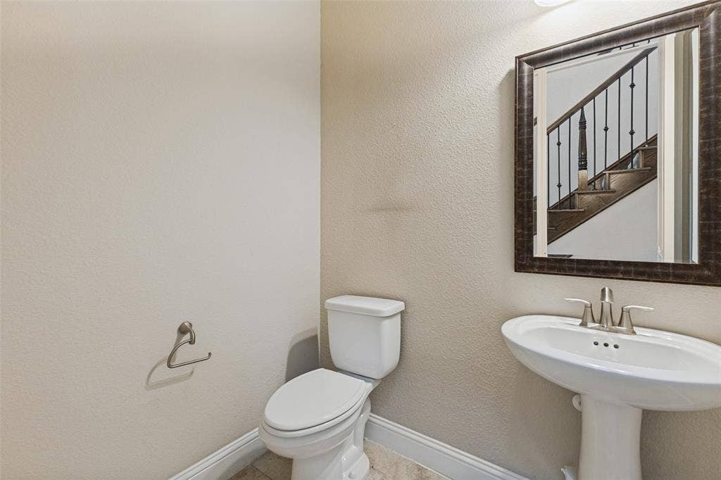 Downstairs guest powder bath with pedestal sink with brushed nickel features and framed mirror