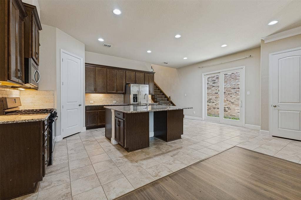 Kitchen featuring a central island, stainless steel appliances, and tile flooring open to living and dining space