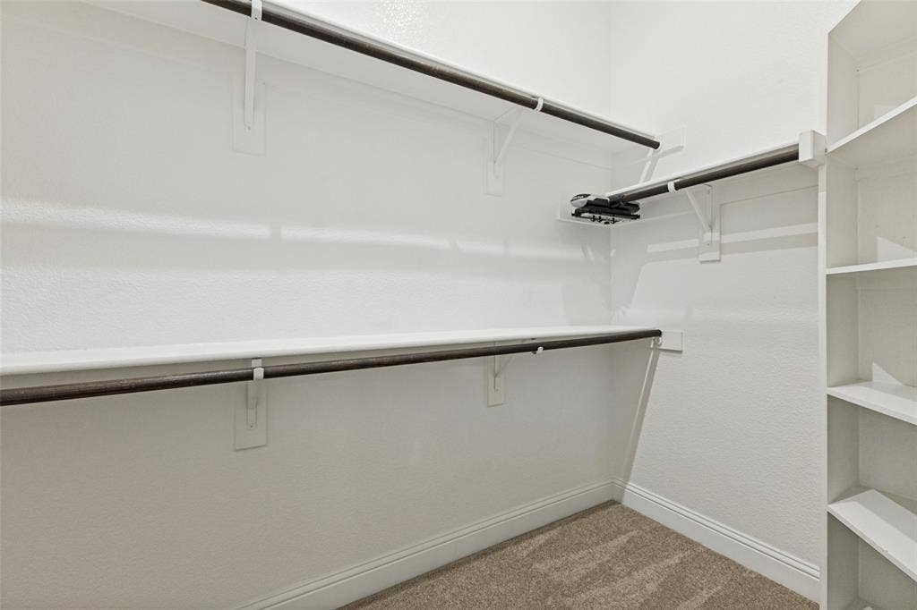 Large primary walk-in closet with built-in shelving and multiple hanging rods