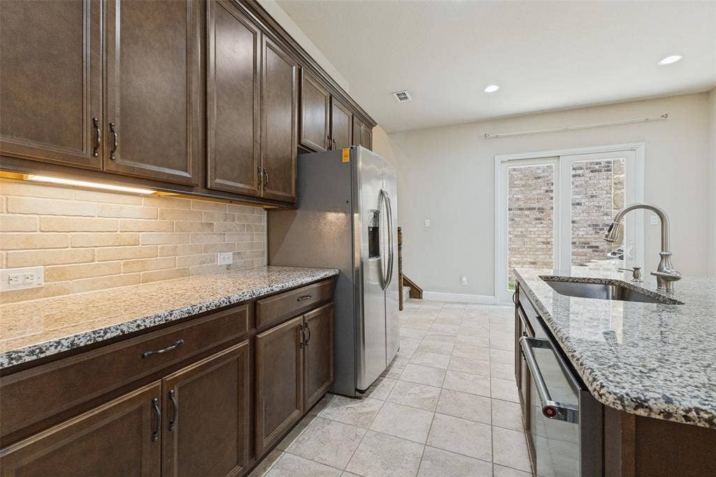 Rich wood-finish cabinetry, granite countertops, subway tiled backsplash
