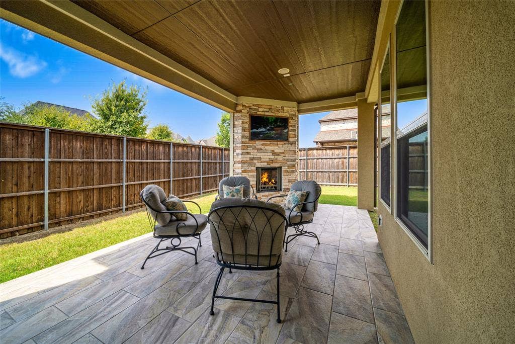 13018 Seattle Slew Street, Frisco, TX 75035 Covered patio with wood-finish ceiling, tiled flooring, and a stacked stone fireplace