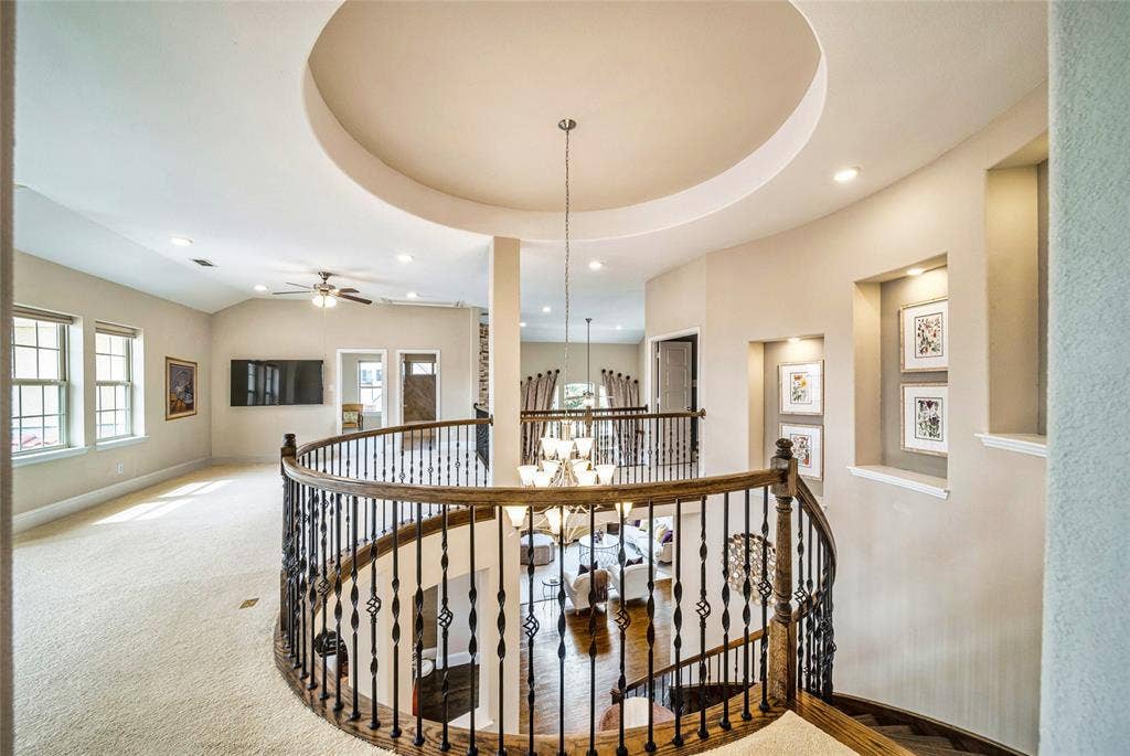 13018 Seattle Slew Street, Frisco, TX 75035 Curved wood-finish handrail with decorative wrought iron spindles, recessed ceiling with accent lighting, built-in wall niches with integrated lighting, vaulted ceiling, and double windows with white trim