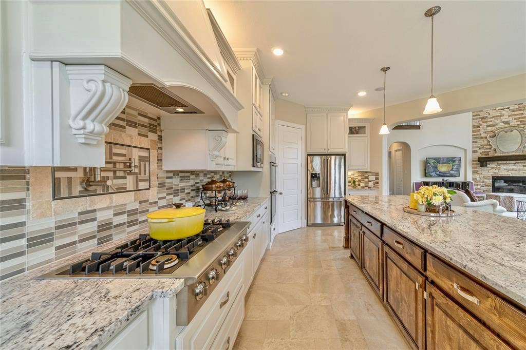 13018 Seattle Slew Street, Frisco, TX 75035 Gourmet kitchen featuring a built-in Electrolux gas range, white cabinetry, granite countertops, and a large level 6 granite entral island