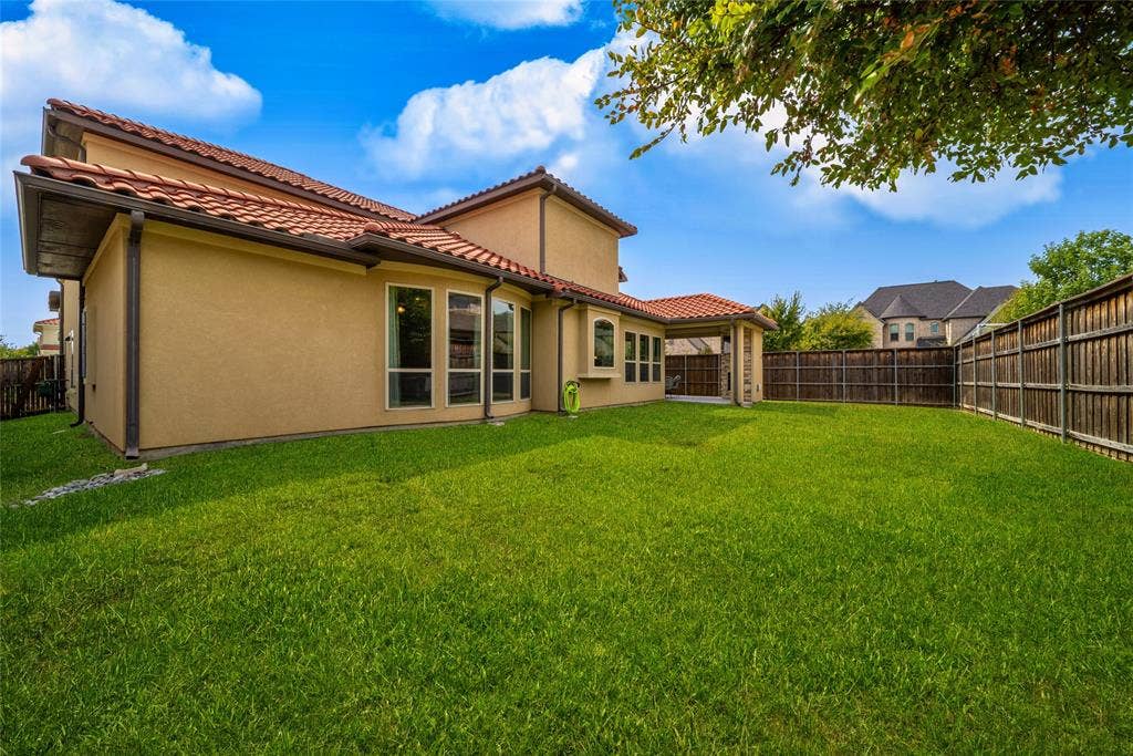 13018 Seattle Slew Street, Frisco, TX 75035 Expansive backyard featuring a manicured lawn, wood fencing, and a covered patio