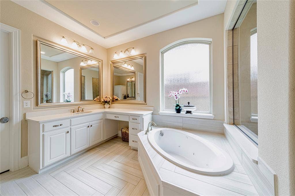 13018 Seattle Slew Street, Frisco, TX 75035 Dual vanity with white cabinetry and integrated makeup counter, complemented by framed mirrors with sconce lighting