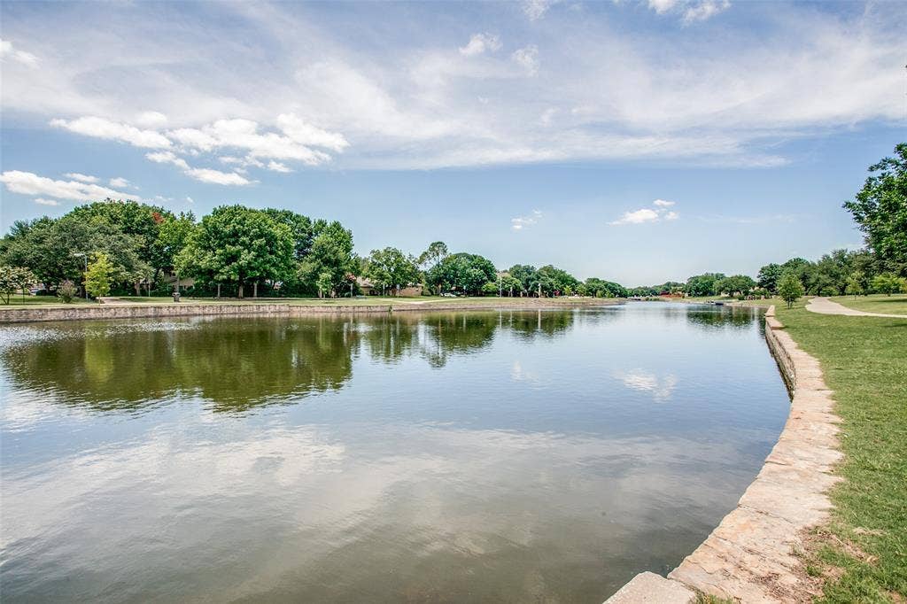 Waterfront property featuring a stone-lined bank, expansive water body, and mature trees