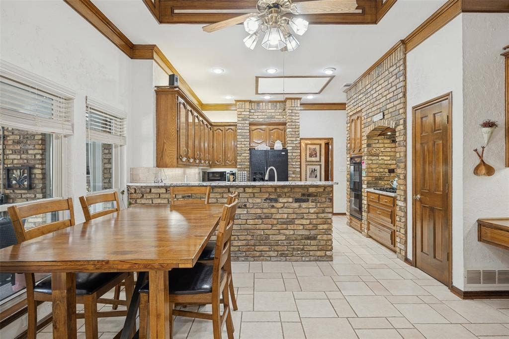 Kitchen and breakfast area featuring brick accents, wood cabinetry, and tile flooring