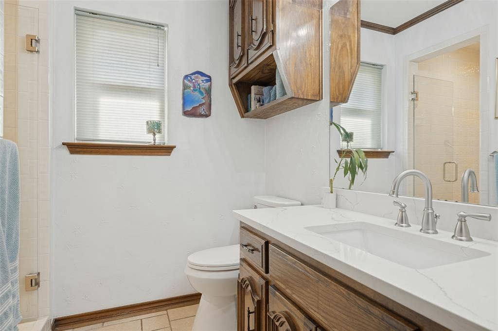 Bathroom featuring a single vanity with wood-finish cabinetry, a white countertop, and a rectangular undermount sink