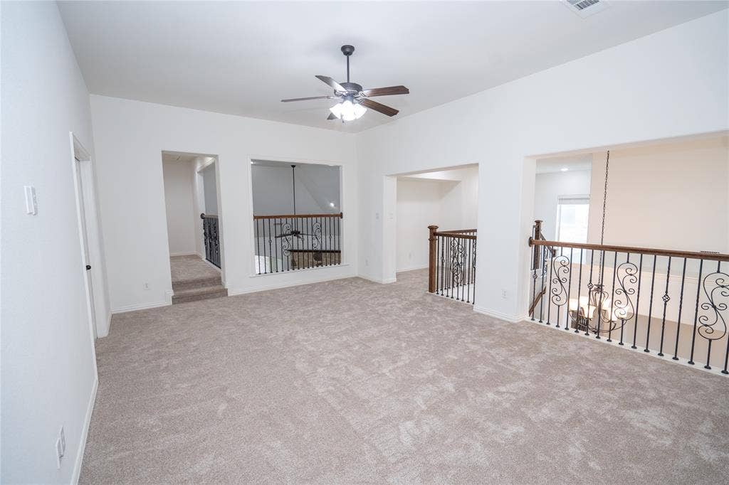 Carpeted open-concept bonus room with a ceiling fan