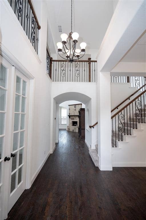 Double-height entryway with wood-finish flooring, an arched doorway, and a chandelier