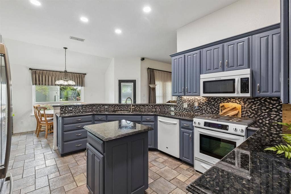 Stylish Kitchen With Custom Cabinetry, Granite Counters, And Modern Mosaic Backsplash