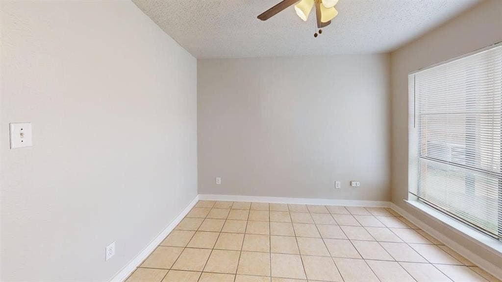 Room featuring a ceiling fan, window with blinds, and tile flooring
