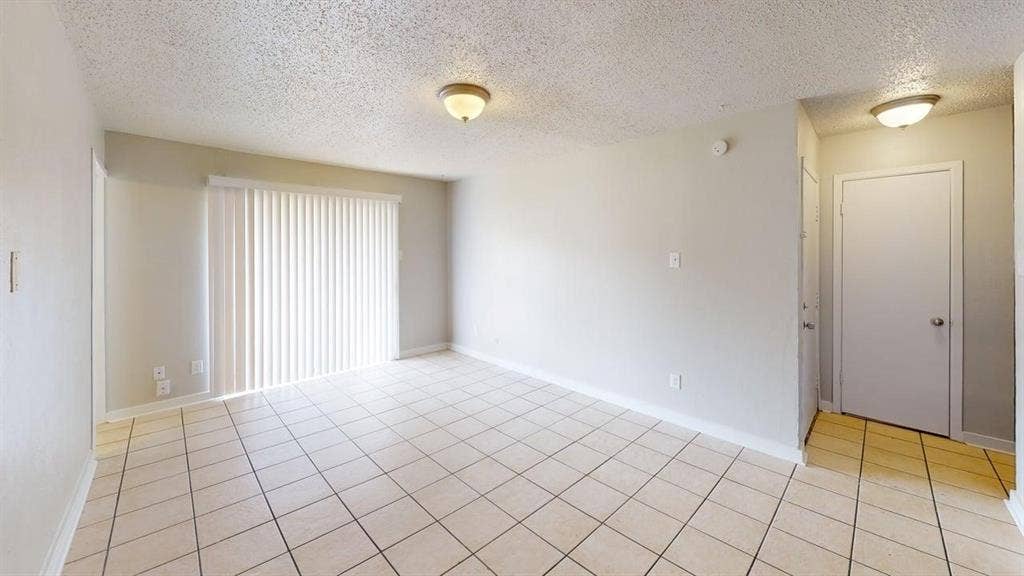 Tile flooring, sliding glass door with vertical blinds, overhead lighting, and neutral wall tones