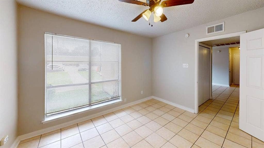 Light-toned tile flooring, neutral wall paint, and a large window with blinds