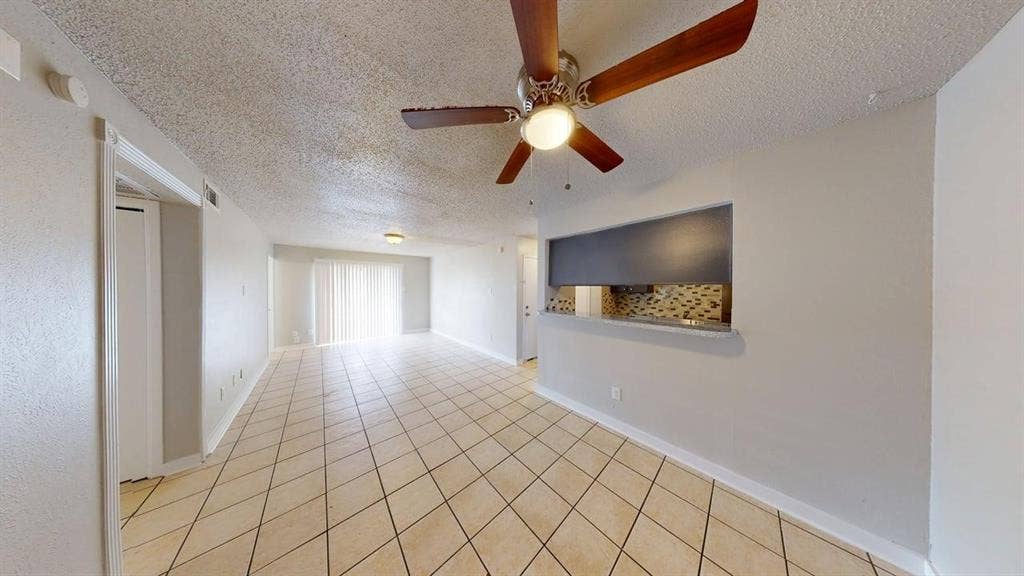 Tile flooring, ceiling fan with light fixture, sliding glass door, pass-through window, and textured walls